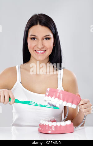 Junge Mädchen zeigen richtig Zähneputzen mit großen Zahnbürste und Backen Stockfoto