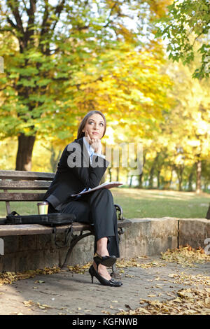 Geschäftsfrau sitzt auf der Bank im Park und denken, outdoor Stockfoto