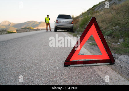 Ein Mann neben einem kaputten Auto Stockfoto