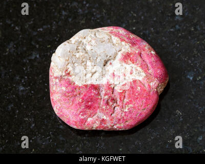 Makroaufnahmen von natürlichen Mineralgestein Muster - trommelsteine thulite Edelstein auf dunklem Granit Hintergrund von leksvik, Norwegen Stockfoto