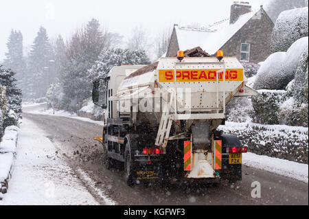 Kalte, schneereiche Winter scene als Streuer Lkw mit Schneepflug, Antriebe, Verbreitung grit & Clearing verlassenen Straße - Hawksworth, West Yorkshire, England, UK. Stockfoto