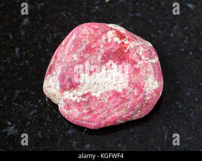 Makroaufnahmen von natürlichen Mineralgestein Muster - polierte thulite Edelstein auf dunklem Granit Hintergrund von leksvik, Norwegen Stockfoto