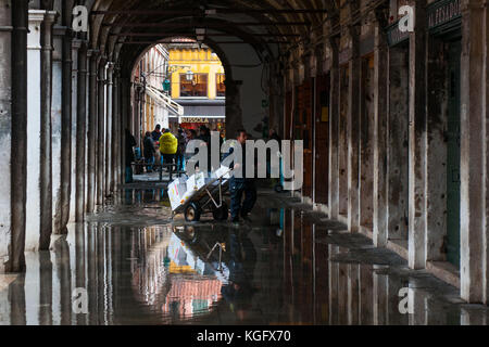 Venedig, Italien. 07. November 2017. Ein Arbeitnehmer kreuzt ein Portikus während einer Flut am 7. November 2017 in Venedig, Italien. Stockfoto