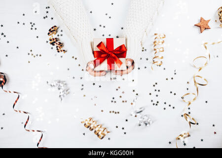 Weibliche Hände halten Geschenk mit roter Schleife Stockfoto
