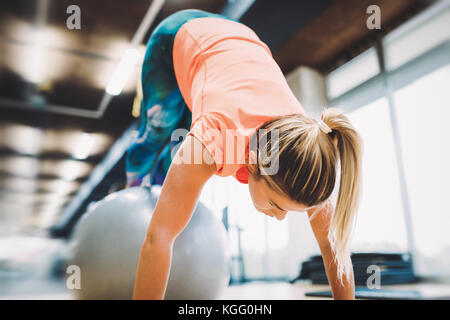 Junge attraktive Frau, Push-ups mit Kugel Stockfoto