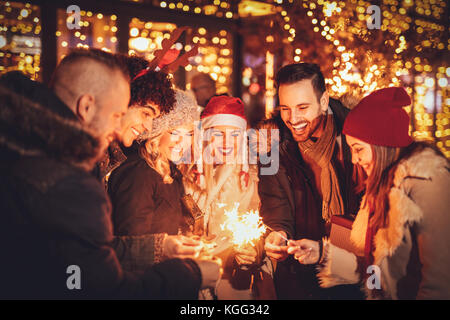 Gruppe der glückliche junge Freunde Spaß mit Wunderkerzen auf Nacht Weihnachtsfeier. Stockfoto