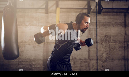 Junge muskulöse Mann Hard Training mit Hanteln für Schultern auf Kreuz fit Training im Fitnessstudio. Stockfoto