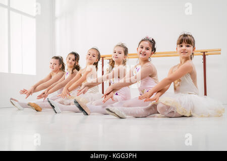 Kleine Mädchen in Kleider zusammen an der Ballettklasse posieren. Blick auf Kamera. Stockfoto