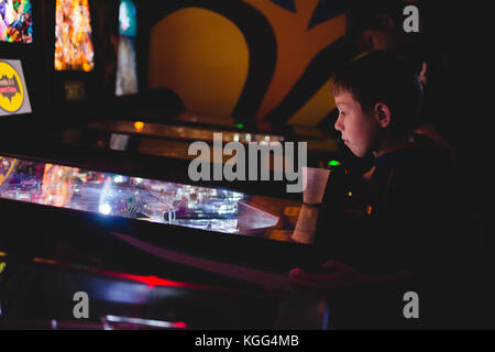 Ein kleiner Junge spielt ein Spiel von pinball an einem traditionellen Arcade in Upstate New York in den USA. Stockfoto