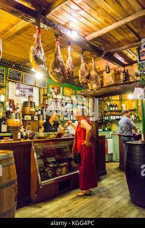 Eine Frau in einem roten Kleid bestellen Wein in La Antigua Abaceria Tapas-Bar, Calle Pureza, Triana, Sevilla, Andalusien, Spanien Stockfoto