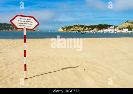 Unbewachter Strand Zeichen in vier Sprachen auf roten und weißen Pfosten am Strand von São Martinho do Porto, Silver Coast, Portugal, Oktober 2017 Stockfoto