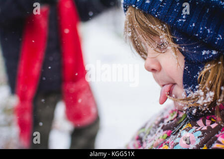 Ein Kleinkind steht außerhalb der Kleidung tragen im Winter mit Schnee um sie herum. Stockfoto