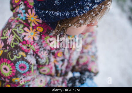 Ein Kleinkind steht außerhalb der Kleidung tragen im Winter mit Schnee um sie herum. Stockfoto