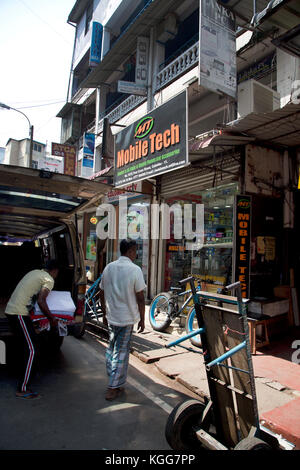 Die pettah Colombo Sri Lanka erste Cross Street Mann entladen Gewebe von der Rückseite eines van außerhalb mobile Tech shop Stockfoto