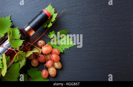 Rose Wein Flasche und frische Weinblätter auf schwarzem Hintergrund, Ansicht von oben, kopieren Raum Stockfoto