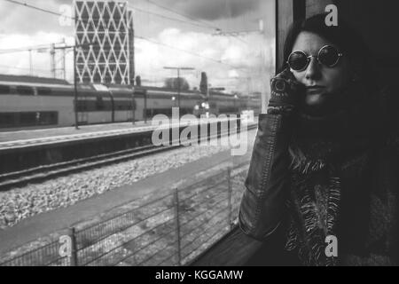 Junge Frau von der U-Bahn saßen am Fenster und trug Lennon Sonnenbrille, Amsterdam, Niederlande Stockfoto