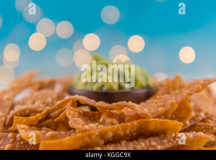 Selektiver Fokus der Tortillachips mit Guacamole im Hintergrund und Bokeh oben Stockfoto