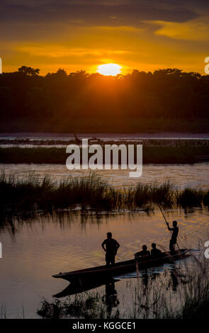 Chitwan, Nepal - November 03, 2017: unbekannter Menschen genießen den schönen Sonnenuntergang, während Sie Kanu Safari sind auf hölzernen Boote Pirogen auf dem rapti River im Chitwan Nationalpark, Nepal Stockfoto