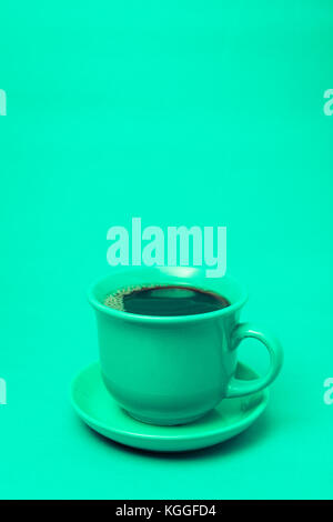 Grüner Becher mit dampfendem heißen Kaffee. Weicher Rauch. Blauer Hintergrund. Vertikales Foto Stockfoto