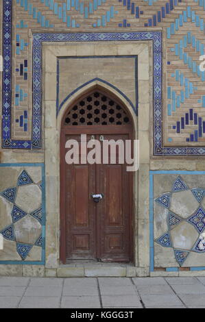 Die hölzerne Tür mit den dekorativen Fliesen auf dem Mausoleum in der Seidenstraße Stadt Turkestan, Kasachstan. Islamische geometrische Muster. Stockfoto