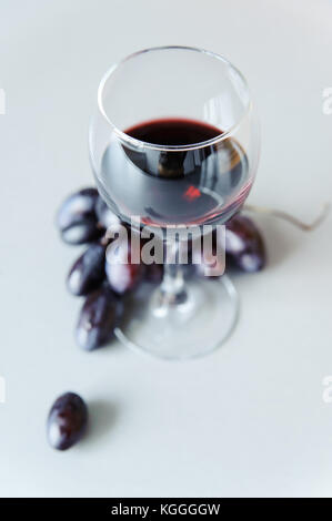 Trauben und einem Glas Weißwein auf grauem Hintergrund Stockfoto