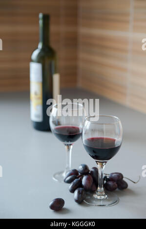 Trauben, zwei Gläser und die Flasche Wein auf dem Tisch. Stockfoto