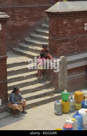 Nepalesische Menschen warten darauf, Trinkwasser mit Kanister in einem alten Brunnen in Kathmandu, Nepal, zu sammeln. Wasserknappheit, Dürre, nach Erdbeben Stockfoto