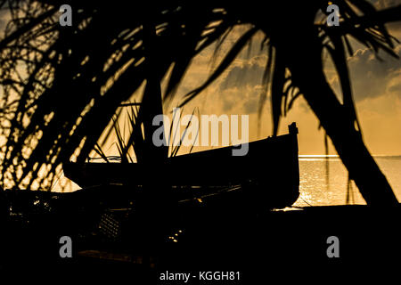 Boot in einem warmen Morgenlicht an einem Strand mit Moody Himmel. Stockfoto