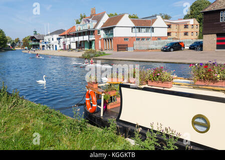 Hausboot-Barge und Studenten rudern auf dem Fluss Cam vor dem Goldie Boathouse CUBC Ruderclub nahe Midsummer Common, Cambridge, England, Großbritannien Stockfoto