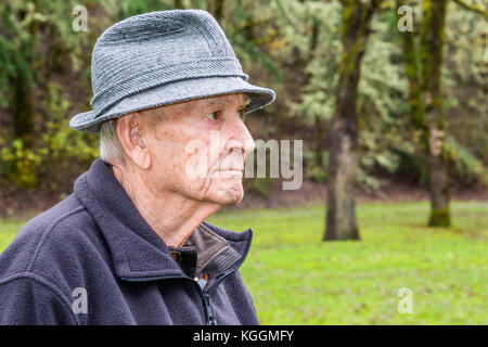 Profil Portrait von gesunden, aktiven schweren älterer Mann mit grauen Tweed Regen Hut und schwarzen Pullover bei einem Spaziergang in einem Park Stockfoto