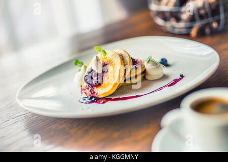 Pfannkuchen und Kaffee. Pfannkuchen mit einer Tasse Kaffee und frische Früchte Heidelbeeren und Kraut Dekoration. traditionellen Frühstück oder Mittagessen im Hotel oder Rest Stockfoto