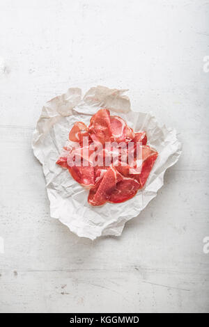 Nach oben Anzeigen Scheiben Prosciutto oder jamon auf Weiß konkreten Hintergrund. Stockfoto