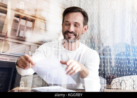 Schöner Mann durch Dokumente in städtischen Cafe suchen Stockfoto