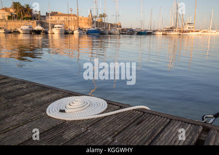 Ordentlich aufgewickelt, weiß Seil auf einem Steg mit Yachten im Hintergrund Stockfoto