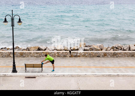Man dehnen und laufen auf der Straße der Stadt am Meer. Junge Athleten männlichen Schulung und Training im Freien in städtische Szene. Sport und Fitness Trainin Stockfoto