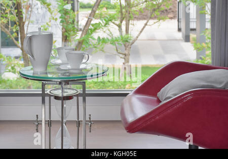 Kaffee auf Glas Tisch mit roten Sessel im Wohnzimmer Stockfoto