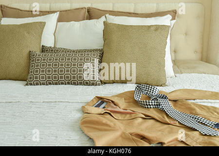 Gelbe Anzug und Krawatte, die Sie im Bett mit braunen und beigen Kissen Stockfoto