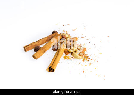 Haufen von Muttern und Zimtstangen auf Weiß. Weihnachten Dessert Lebensmittel Backzutaten. Cinnamon Rolls, Mandeln, Haselnüsse, Walnüsse, Cashewnüsse. Stockfoto