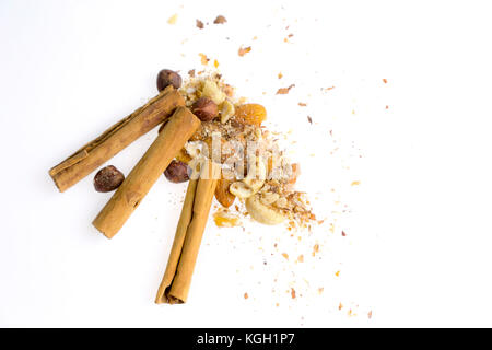 Haufen von Muttern und Zimtstangen auf Weiß. Weihnachten Dessert Lebensmittel Backzutaten. Cinnamon Rolls, Mandeln, Haselnüsse, Walnüsse, Cashewnüsse. Stockfoto