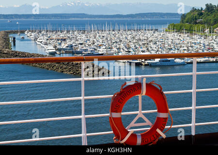 Eine Marina in Seattle, Washington, gesehen vom Deck eines Kreuzfahrtschiffes mit einem Geländer und Lebensretter im Vordergrund. Stockfoto