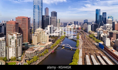 Erhöhte Nahaufnahme Blick in die Stadt Melbourne CBD über den Fluss Yarra Gewässer und Flinders Station Bahnsteige zwischen Vororten von hohen Gebäuden Stockfoto