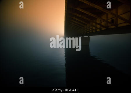 Einen schönen Abend Nebel über dem Fluss im Stadtzentrum. Brücke im Nebel, Herbst Landschaft. Weiche, verschwommen, Misty suchen. Bunt, mystische Stadtbild von Ri Stockfoto