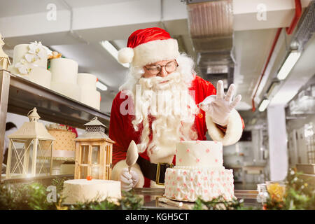 Santa Claus eine Konditoren einen Kuchen in der Küche auf Weihnachten da Stockfoto