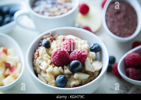 Schüssel gekochten Rote Quinoa mit Beeren und Apple Frühstück in einem Glas, kleine Schüsseln mit Himbeeren, gehackte Äpfel und Heidelbeeren, runde Scheibe von App Stockfoto