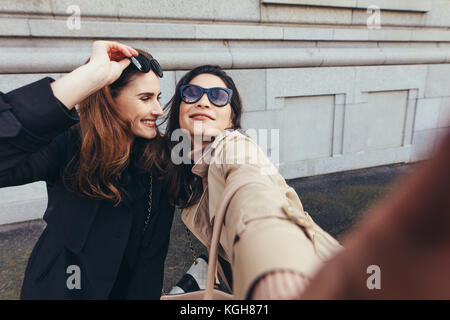 Beste Freunde ein selfie draußen auf der Straße. Zwei junge Frauen, die ein Selbstportrait außerhalb der Stadt. Stockfoto