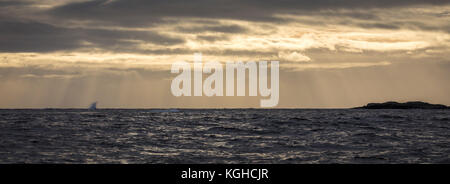 Sonnenstrahlen über stürmischem Meer, mit warmem Himmel und blauem Ozean. Stockfoto