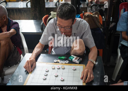 03.11.2017, Singapur, Republik Singapur, Asien - ältere Männer spielen Chinesisches Schach, auch bekannt als Xiangqi, an einem kleinen öffentlichen Platz in Chinatown. Stockfoto