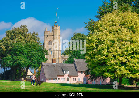 Village Green UK, Blick über den Dorfplatz in Richtung der mittelalterlichen Kirchturm und traditionellen rosa Cottages in Cavendish, Suffolk, England, Großbritannien Stockfoto