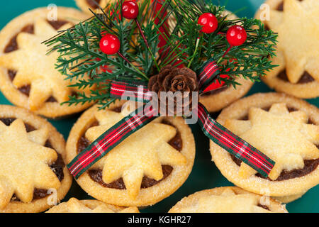 Weihnachten acorn und tartan Motiv mit Beeren auf eine Platte, die von frisch gebackenen Sterne gekrönt Mince Pies Stockfoto