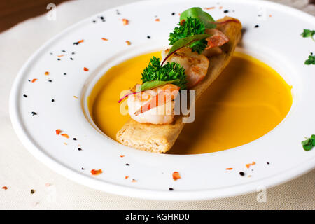 Kürbis Suppe pürieren mit Croutons und Garnelen in die weiße Platte Stockfoto